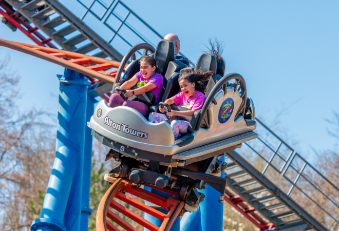 "Two riders in a spinning rollercoaster car on a curved track at Alton Towers."