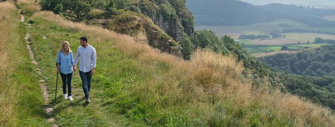 Couple walking at Sutton Bank, woman is using a walking stick. 