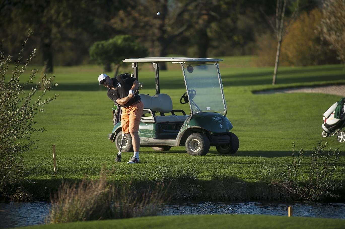 "Photo of golfer with a disability mid swing on the golf course"