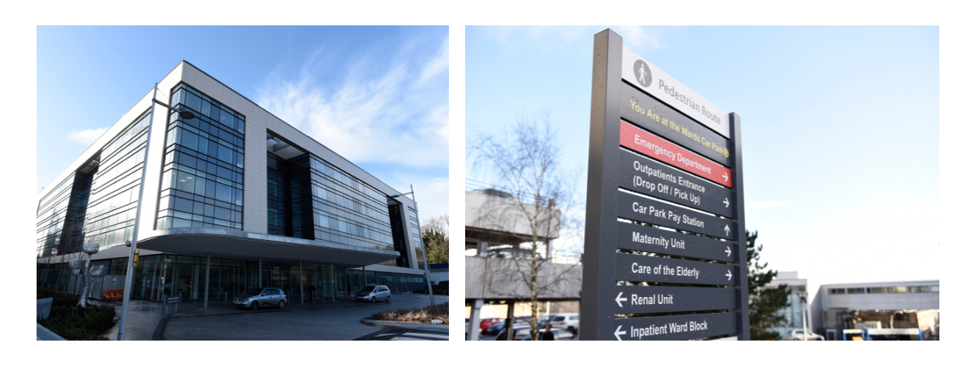 "Two images side by side. The image on the left is Ulster Hospital. It is a large, modern building with multiple floors. There is a drop off point at the front of the building and two cars are parked. There is a canopy above the drop off point. The image on the right is external hospital signage with arrows indicating where parking and departments are located. The image is focused on the signage and has a slightly blurred background of buildings, a car park and a couple of trees."