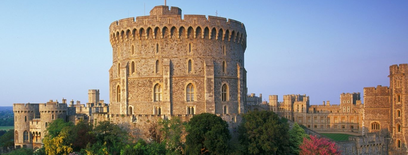 Drone shot of castle exterior walls, clear blue sky in the background, castle fills the screen