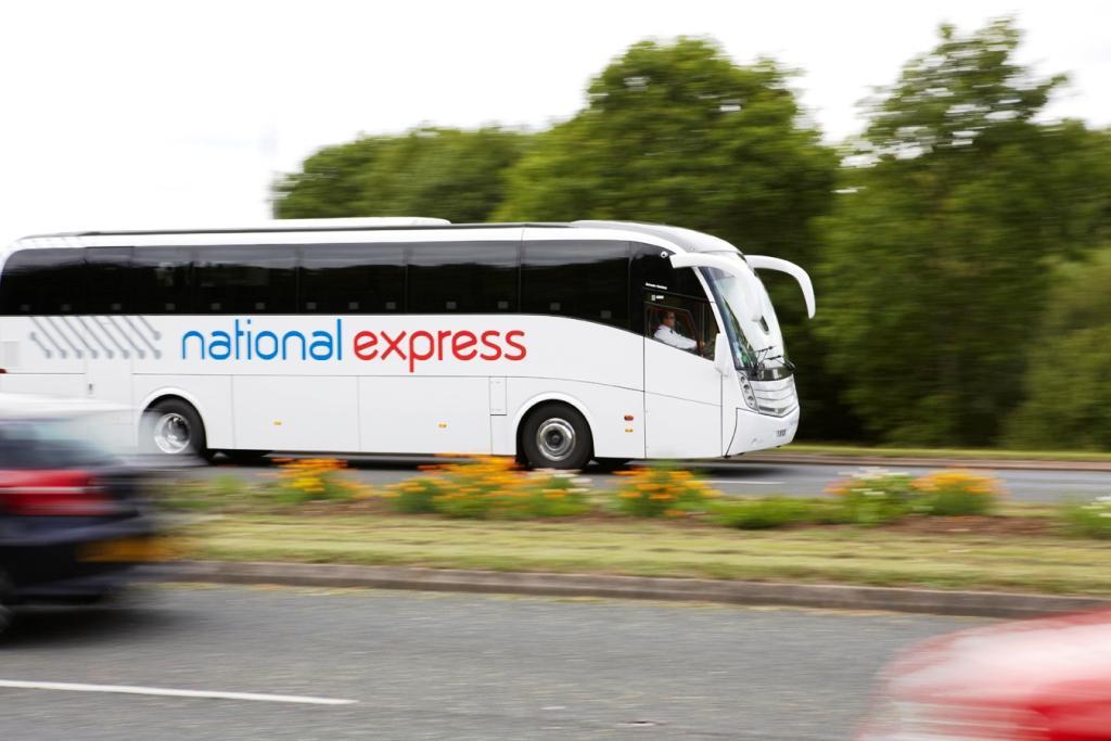 "A photo of a white National Express coach on a road, with National written in blue and Express written in red. The background is blurred to focus on the coach."