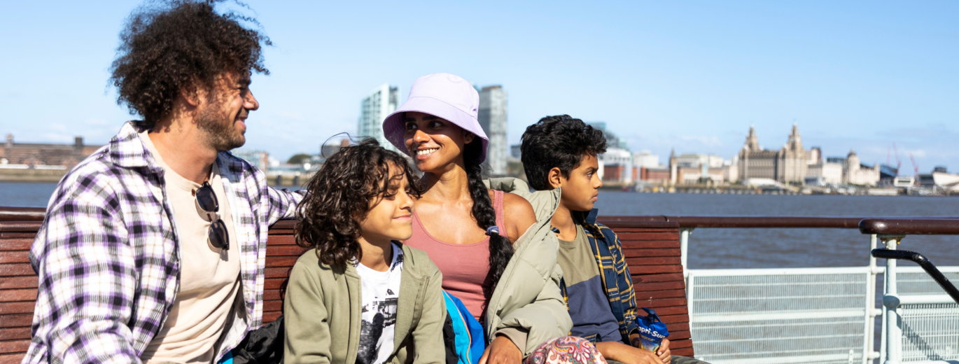 A family sat on a boat in the sunshine on the mersey 