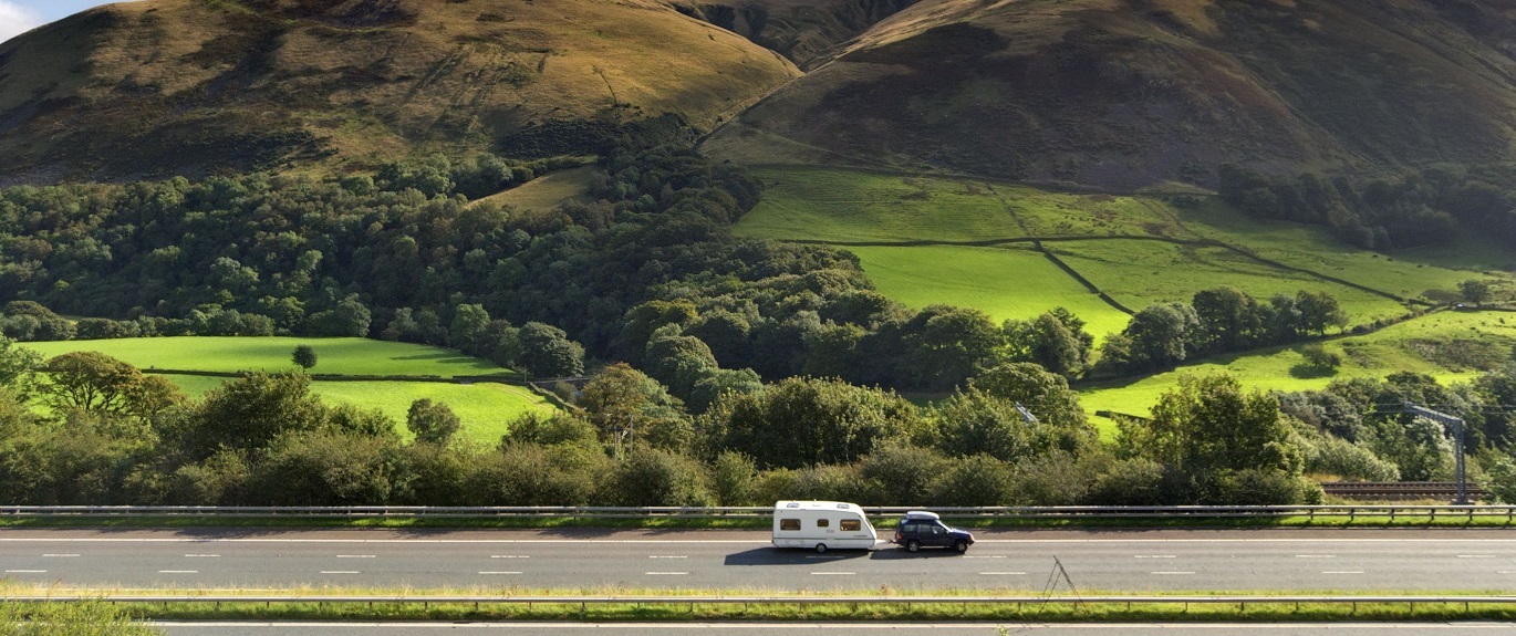 Photo of a car towing a caravan on an empty motorway
