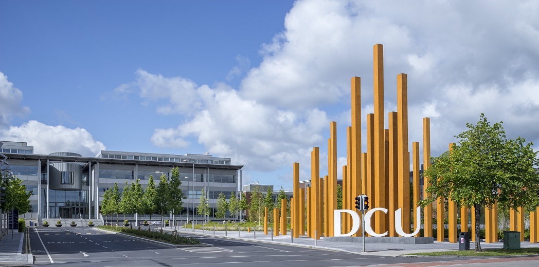 "Dublin City University building with sign and large standing structure in foreground"