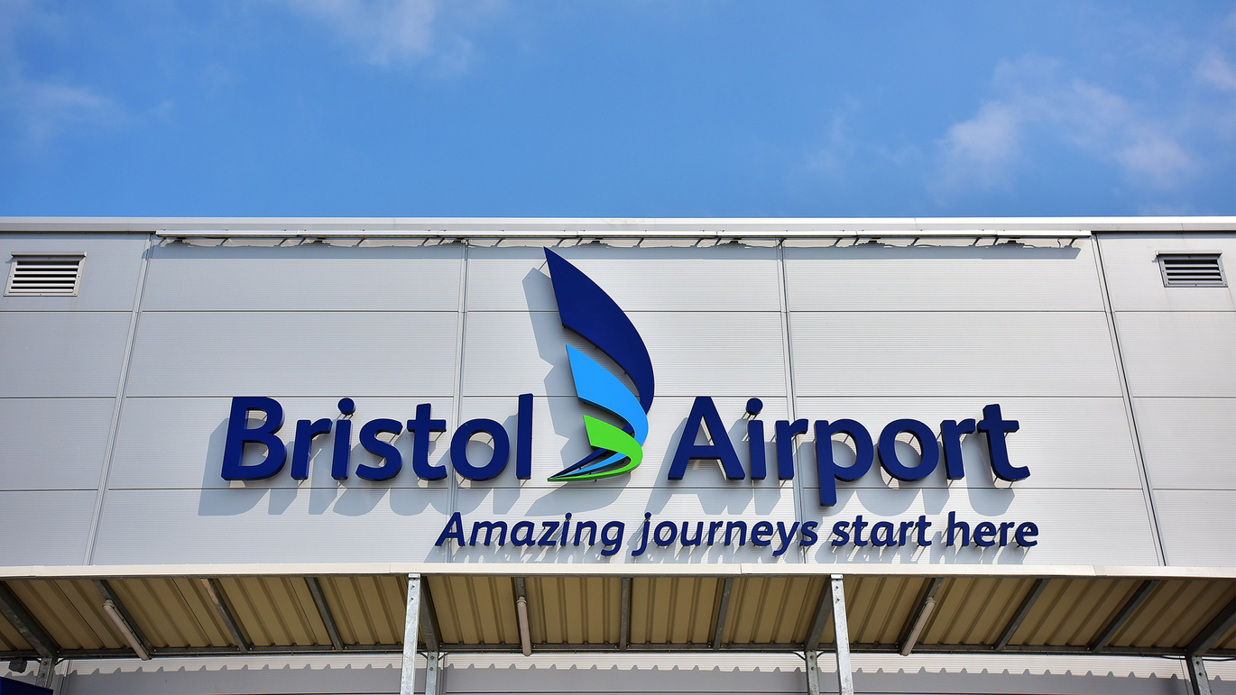 "Bristol Airport outside welcome sign at the top of the building with their name and tag line 'Amazing journeys start here' underneath."