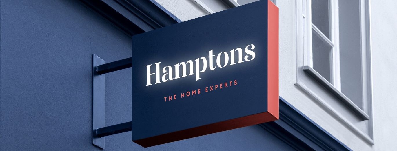 "Close up image of a Hamptons sign, hanging out from a shop front."