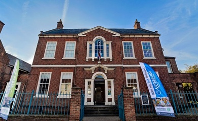 Bassetlaw Museum, a grand historic building in Retford with open blue gates and signage around the entrance