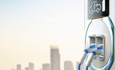An electric vehicle charging point, with a cityscape of tall buildings in the distance.