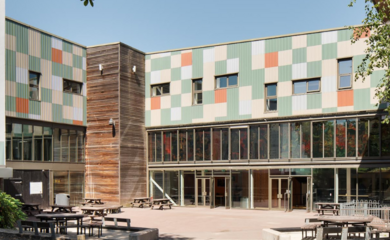 The Midlands Arts Centre Building, a modern structure with green and orange tiles, level access doors, and a courtyard with benches directly outside.