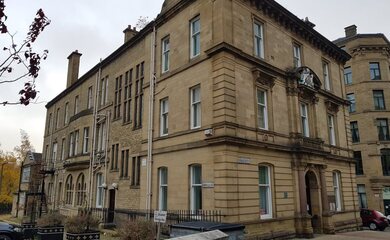 Outside of Inspired Neighbourhoods building, a historic building with several floors. Outside there is a sign for a disabled parking bay near the front door.