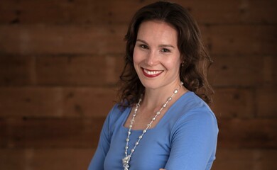 A woman with brown hair wearing a blue top