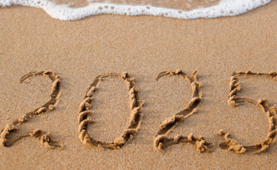 An inscription of 2025 written in the sand by the sea shore. 