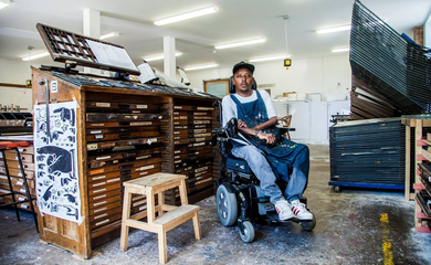 Portrait of Christopher Samuel - black man sitting in a power chair in an art workshop