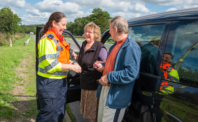 Couple and highways agent standing by a vehicle